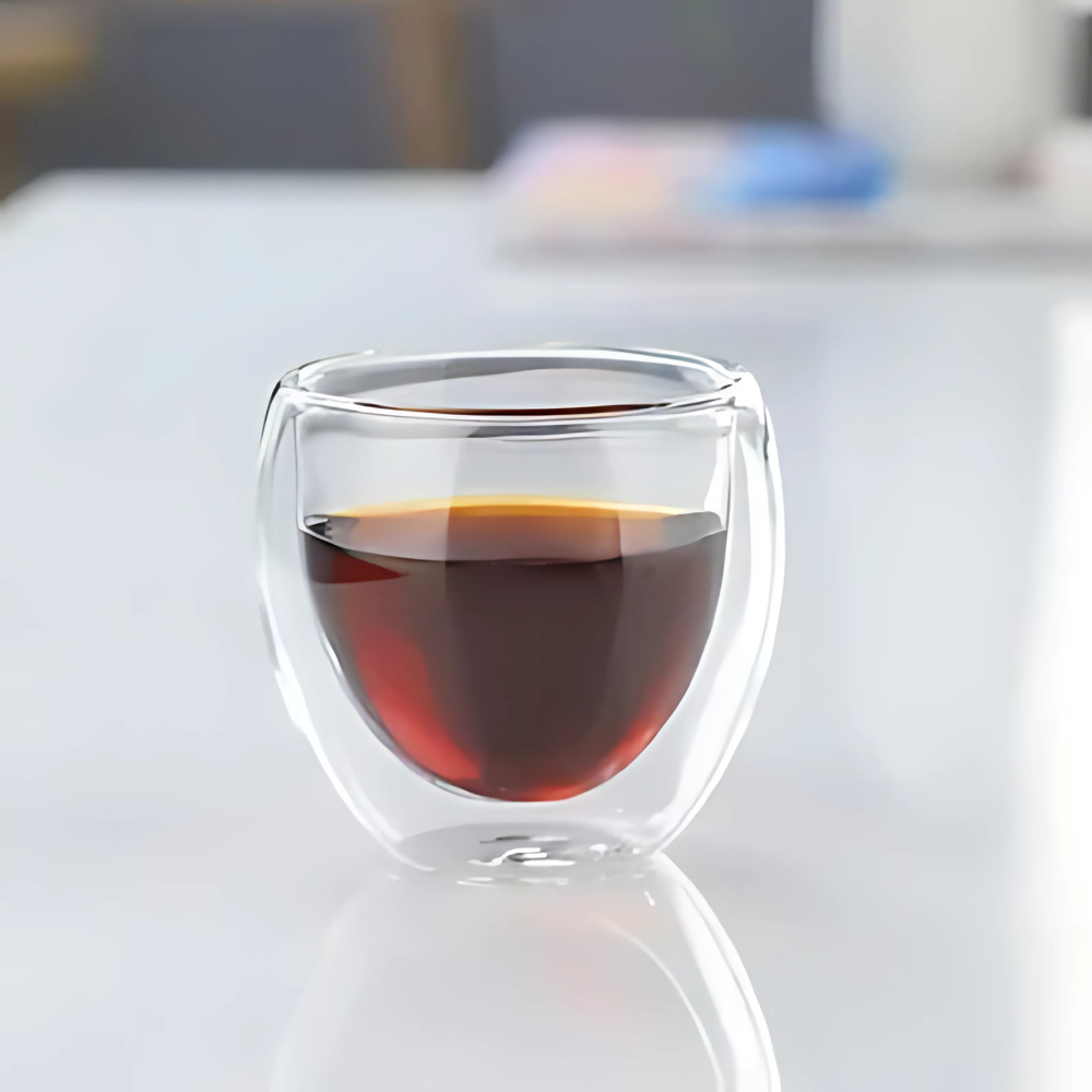Double wall glass tea cup resting on a saucer, clear insulated design