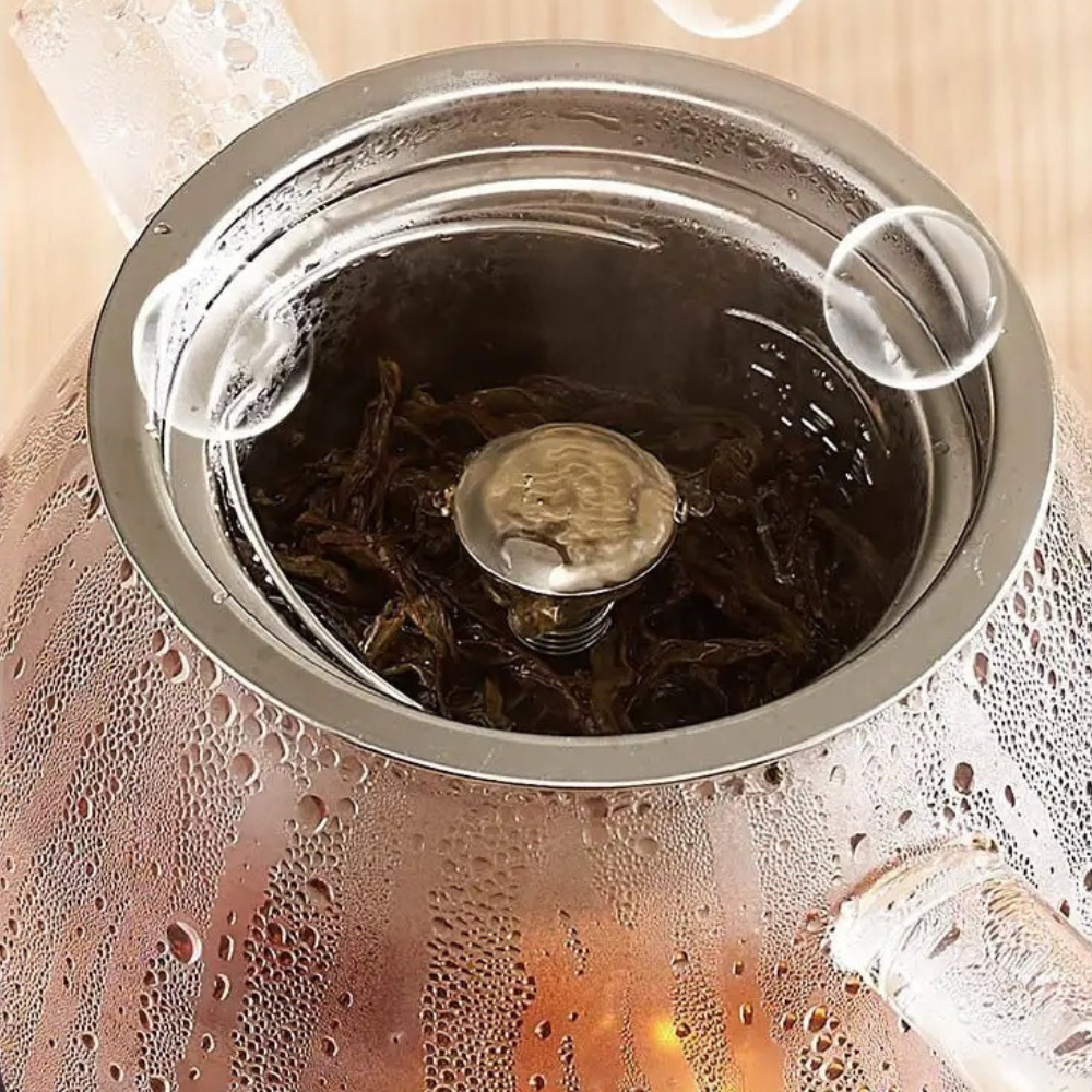 Borosilicate glass teapot filled with hot water and tea leaves steeping