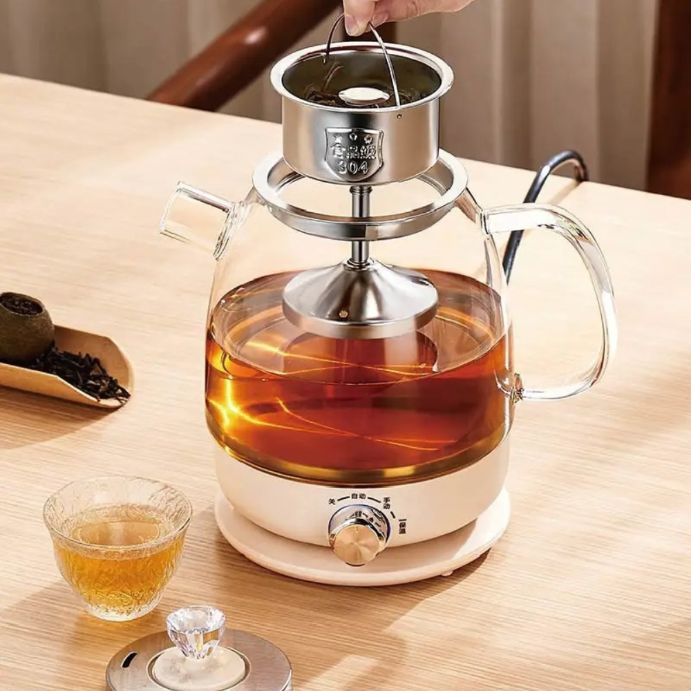 Electric glass teapot with poured cup of tea on wooden table, keep-warm base lit
