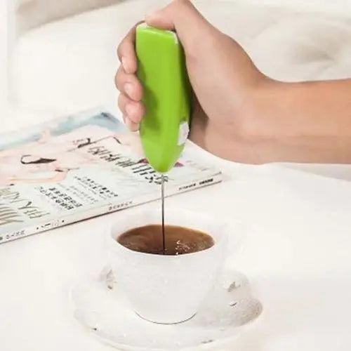 Battery-powered matcha frother beside a fresh green matcha cup