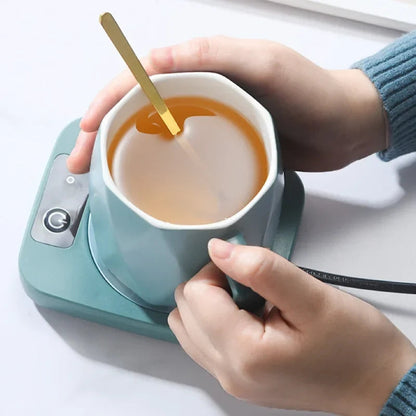 Electric mug warmer in blue with ceramic mug on top, desk setup