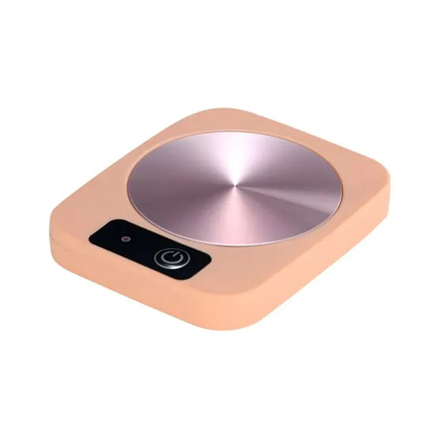 Electric mug warmer with glass cup of hot tea on heating plate