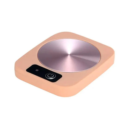 Electric mug warmer with glass cup of hot tea on heating plate
