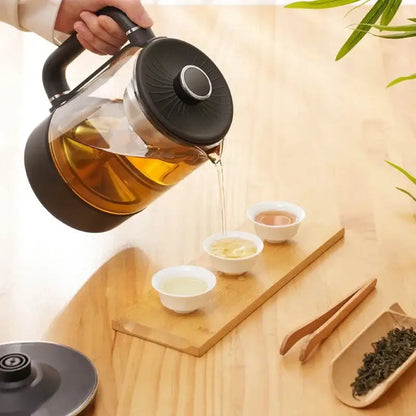 Electric tea maker pouring brewed loose-leaf tea into ceramic cup