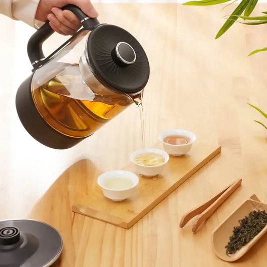 Electric tea maker pouring brewed loose-leaf tea into ceramic cup