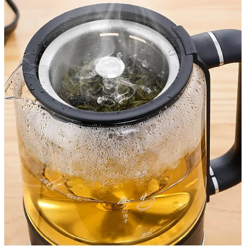 Loose-leaf green tea steeping inside the glass carafe of the electric tea maker
