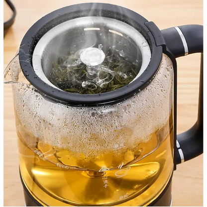 Loose-leaf green tea steeping inside the glass carafe of the electric tea maker