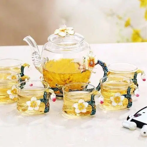 Floral glass teapot set with six matching clear cups on table