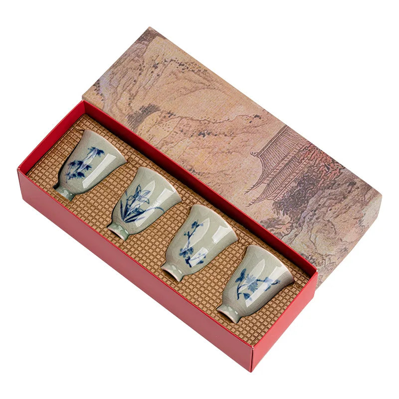 Fabric-lined gift box open showing four porcelain cups in individual padded compartments