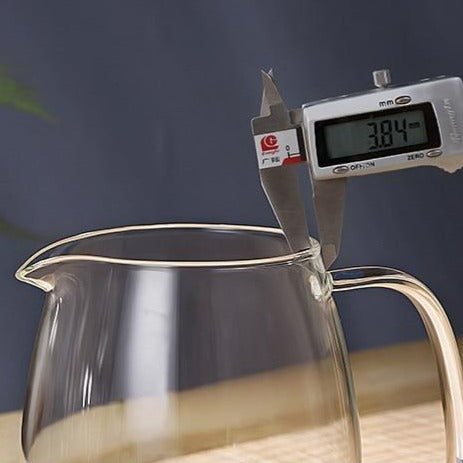 Clear glass teapot on wooden table with flowering tea in water