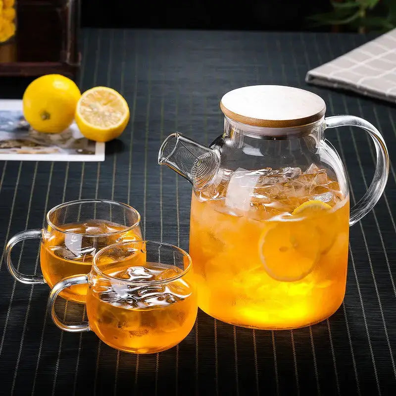 Glass iced tea pitcher with bamboo lid styled on a table with fresh herbs