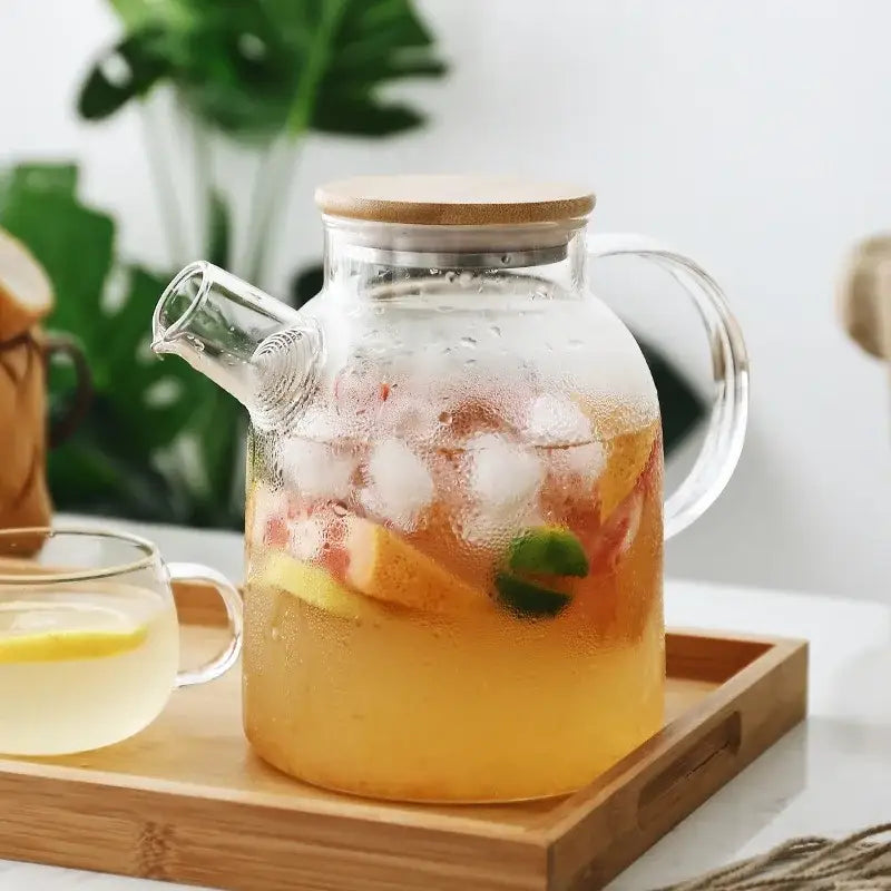 Glass cold-brew pitcher with iced tea, lemon slices, and mint visible through clear glass