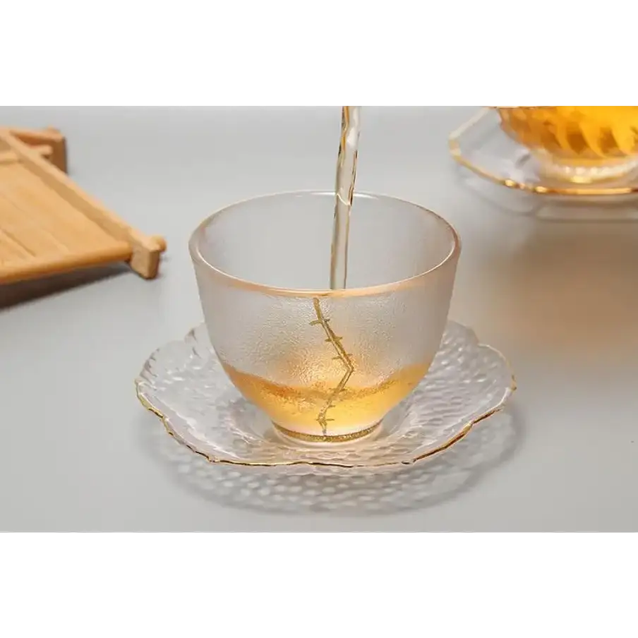 Clear glass saucer with a teacup and teapot