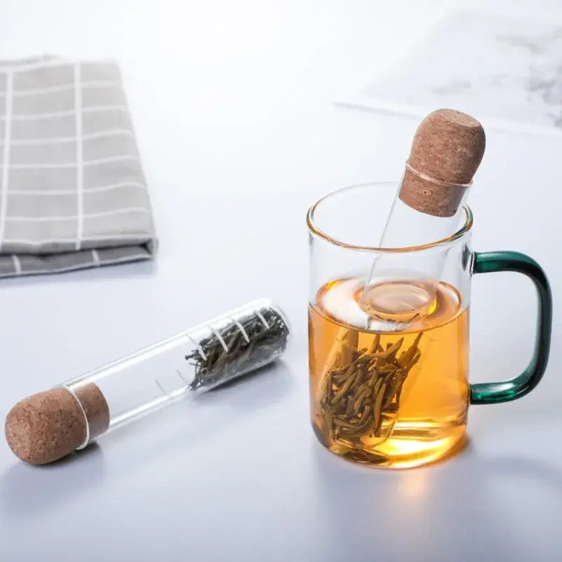 Clear glass tea infuser with borosilicate filter resting on a mug rim