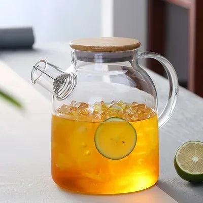 Glass teapot for blooming tea pouring into ceramic cup, cozy kitchen