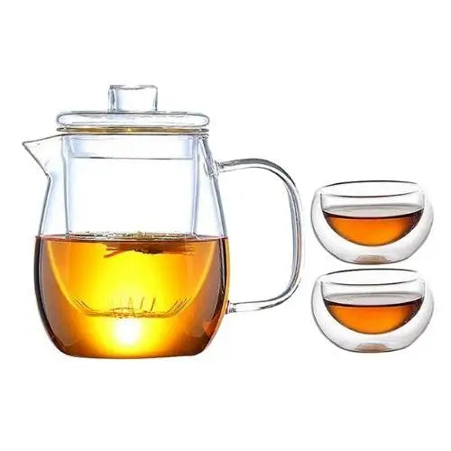 Glass teapot set with two small tea cups on table