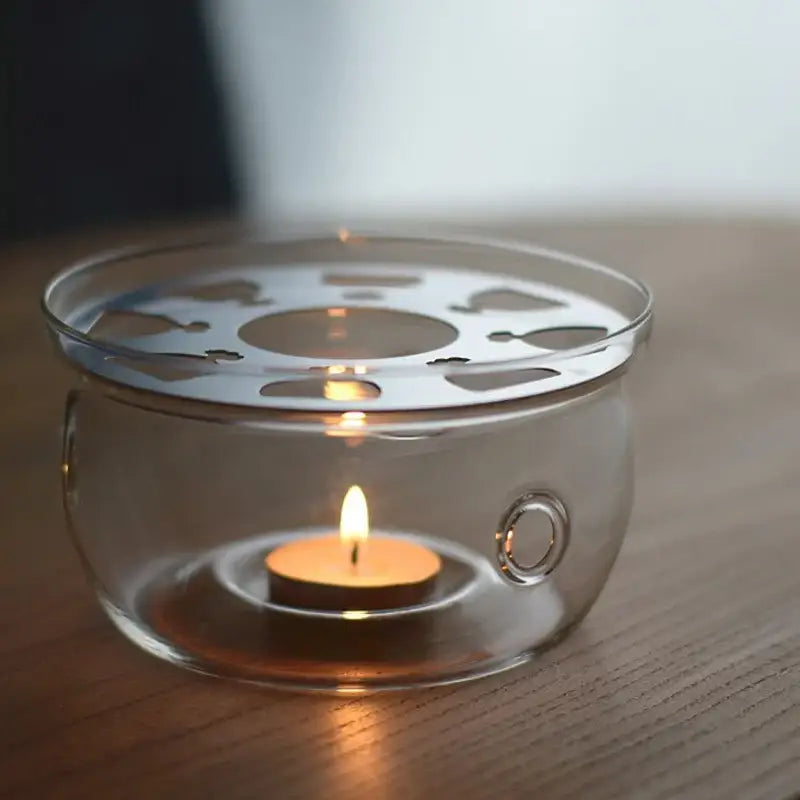 Glass teapot warmer supporting a ceramic teapot from below