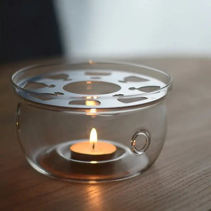 Glass teapot warmer supporting a ceramic teapot from below