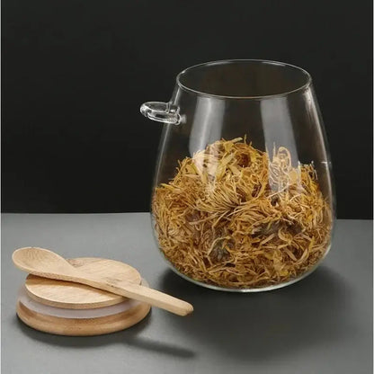 Glass teapot with bamboo lid next to a poured cup of tea, loose-leaf brewing moment