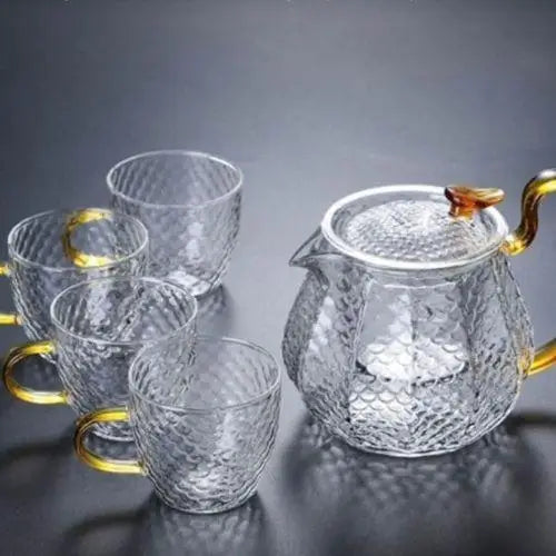 Glass teapot and six matching tea cups set on a table