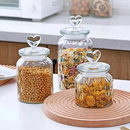 Glass teapot with heart lid placed on a wooden kitchen table, morning tea setting
