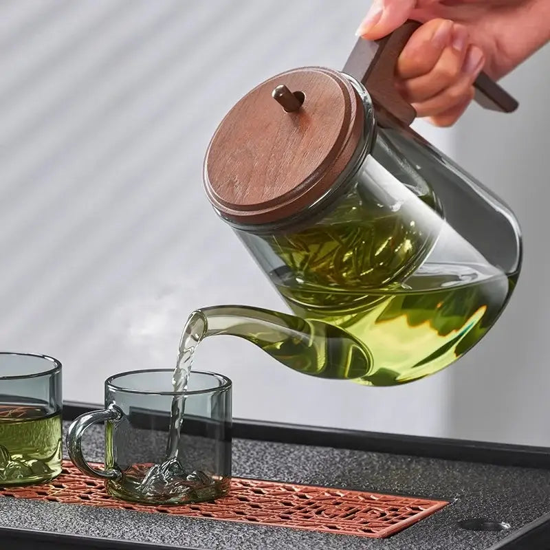 Pouring tea from glass teapot into cup