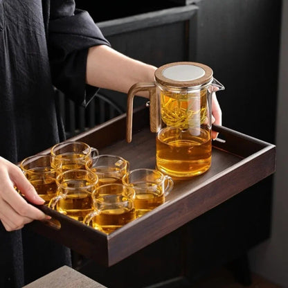 Loose oolong tea leaves fully opened inside the stainless steel infuser basket of the glass teapot