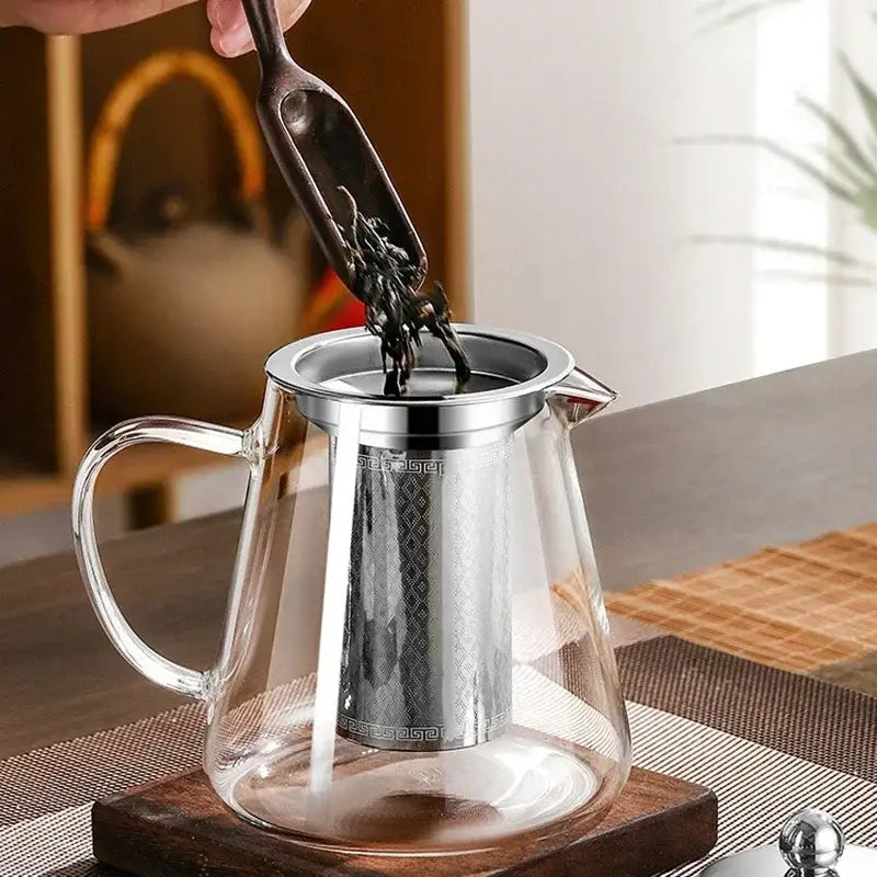 Glass teapot with cup of tea beside it