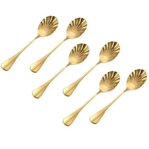 Gold shell teaspoons resting beside a ceramic tea cup and saucer