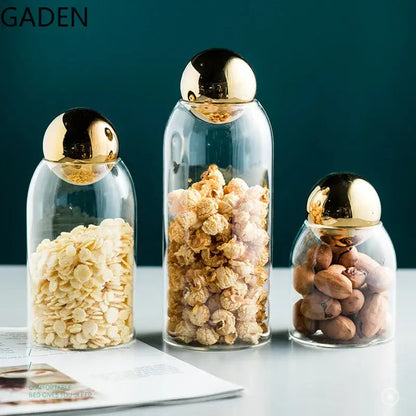Clear glass tea jar with golden airtight lid and loose leaf tea inside