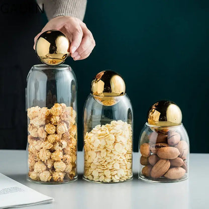 Glass tea canister with golden lid holding tea bags on a cozy kitchen counter