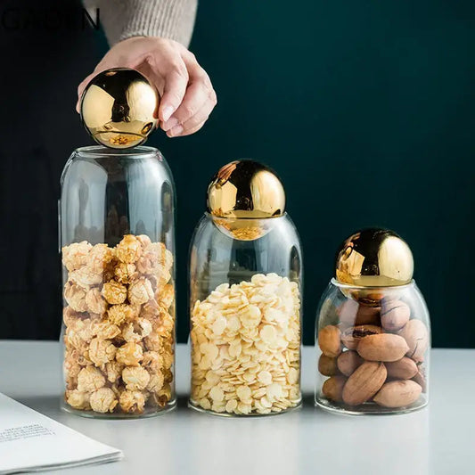 Glass tea canister with golden lid holding tea bags on a cozy kitchen counter