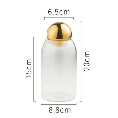 Medium golden glass tea canister with airtight lid on neutral background