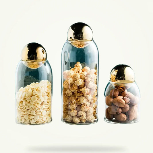 Golden glass tea canister with airtight golden lid, front view on plain background