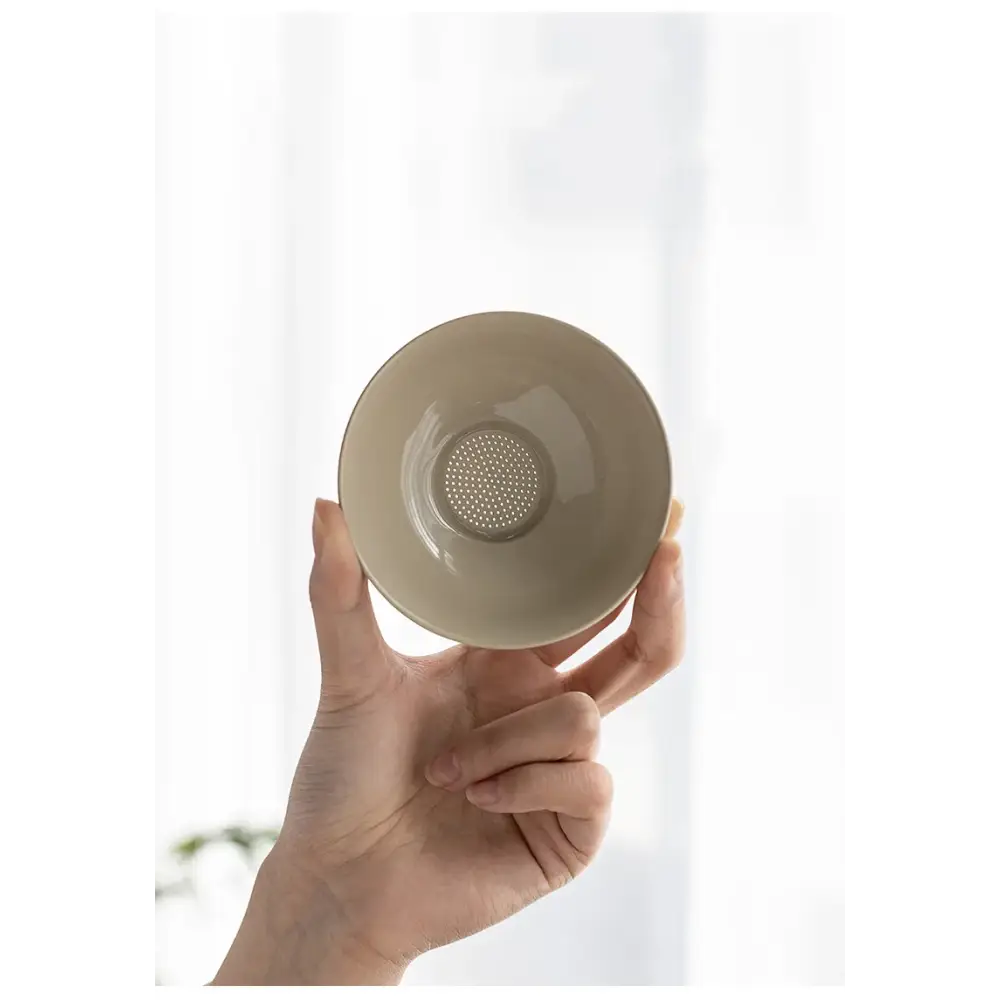 Tea strainer resting on a white porcelain teapot
