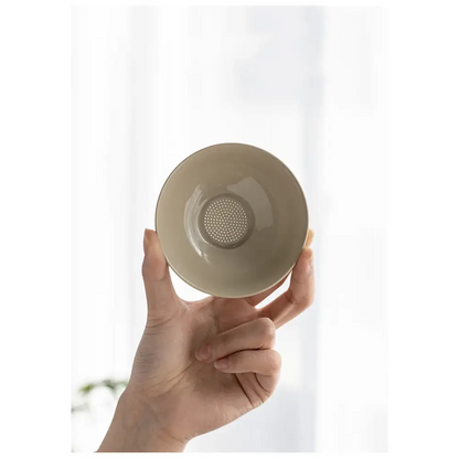 Tea strainer resting on a white porcelain teapot