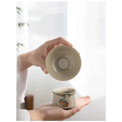 Ceramic tea strainer being used over a glass cup