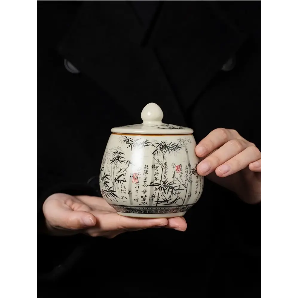Decorative ceramic tea storage canister with bamboo artwork on kitchen shelf