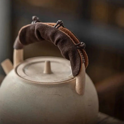 Cozy teapot handle cover in yellow on a ceramic teapot