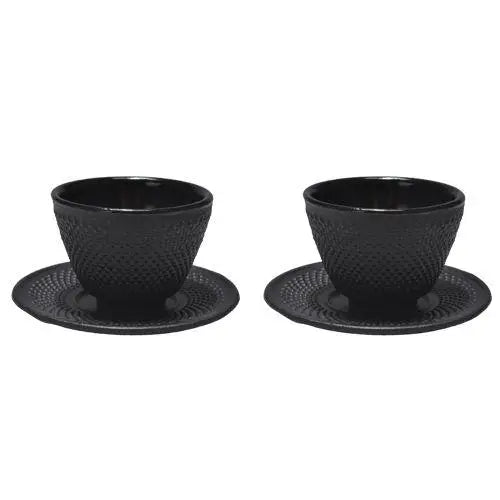 Pair of cast iron tea cups with matching saucers on linen cloth