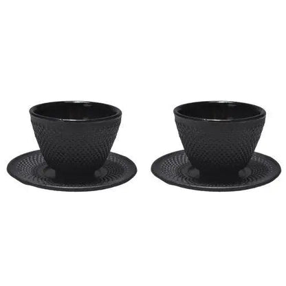 Pair of cast iron tea cups with matching saucers on linen cloth
