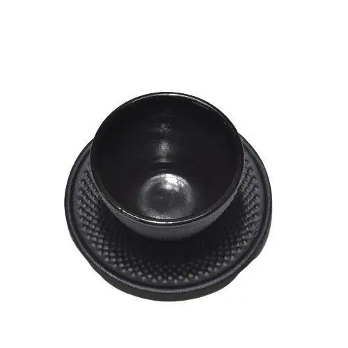 Black cast iron teacup with saucer viewed from above on dark table