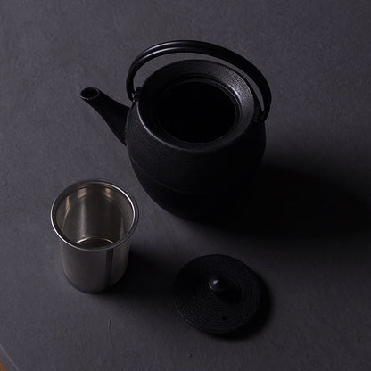 Cast iron teapot pouring loose-leaf tea into white cup
