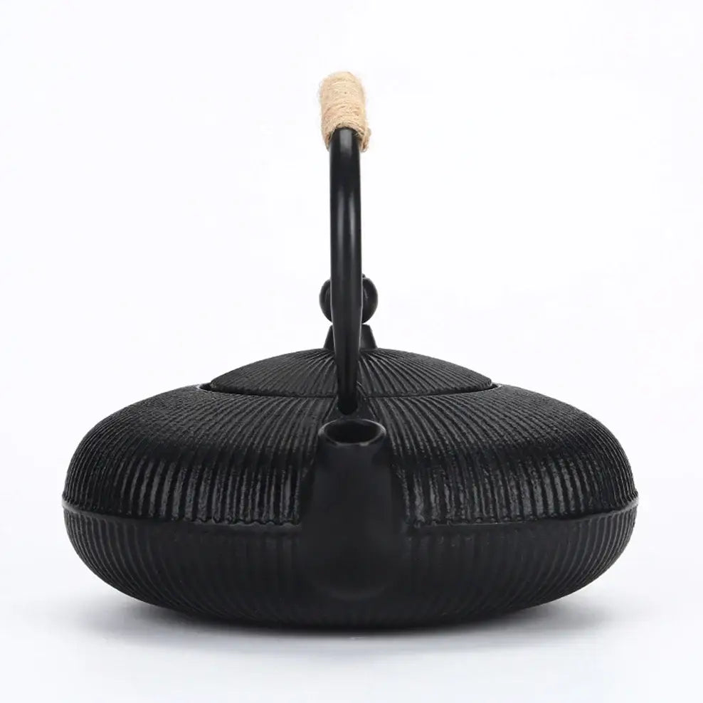 Cast iron teapot pouring hot tea into cup