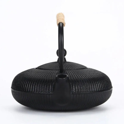 Cast iron teapot pouring hot tea into cup