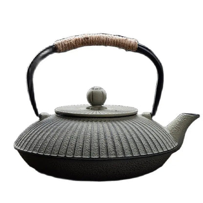 Japanese cast iron teapot on wooden table beside ceramic teacup, afternoon tea setup