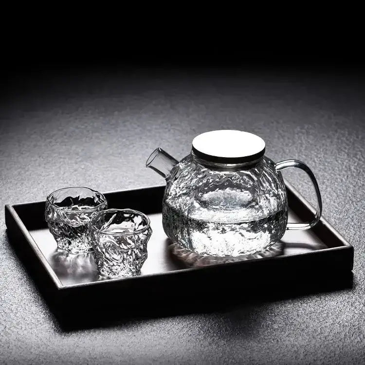 Japanese style glass teapot on wooden table next to a teacup