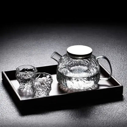 Japanese style glass teapot on wooden table next to a teacup