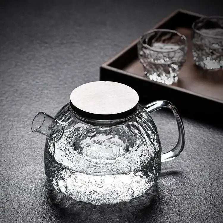 Clear glass teapot filled with hot water and loose tea leaves steeping