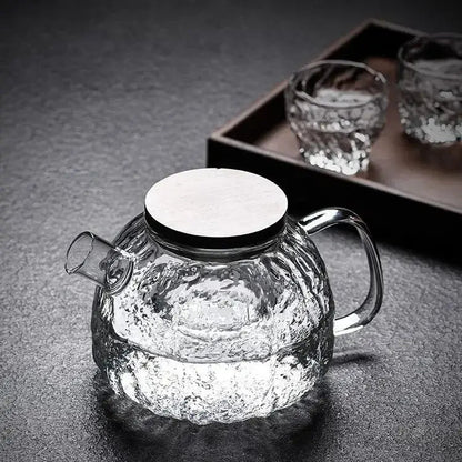 Clear glass teapot filled with hot water and loose tea leaves steeping